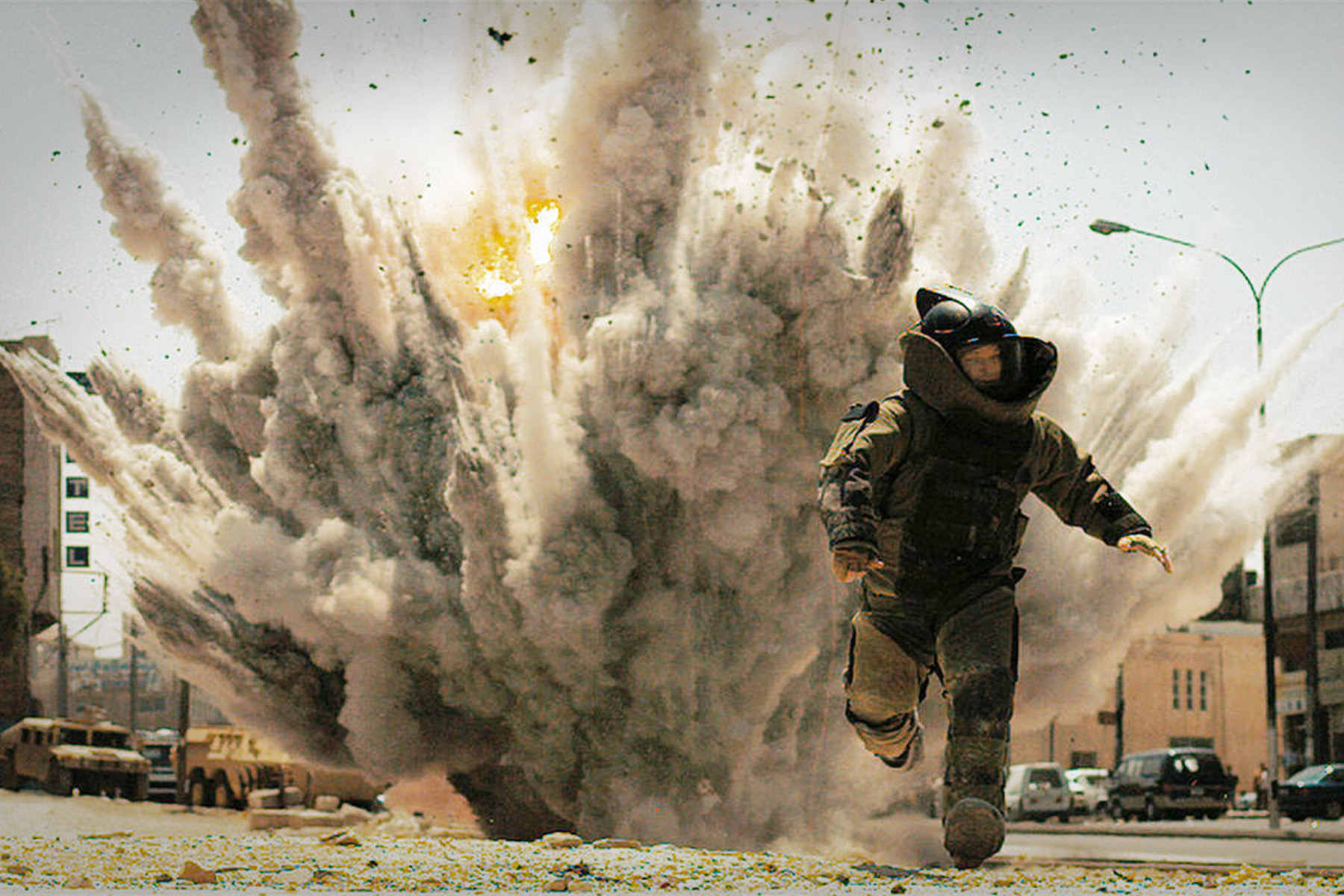 An image of a bomb defused expert walking away from an exploding bomb