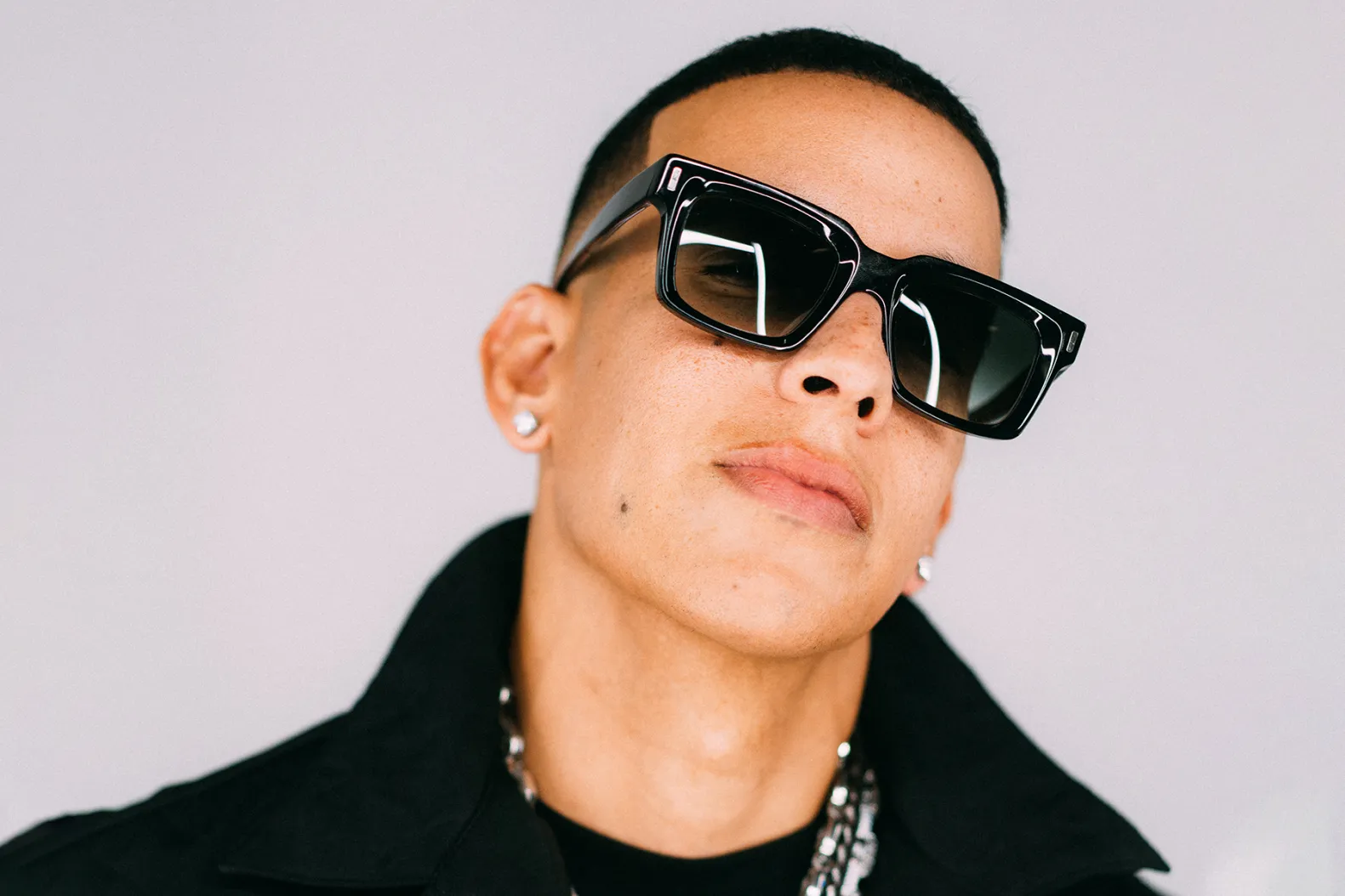 A portrait photo of Daddy Yankee wearing sunglasses and a black top